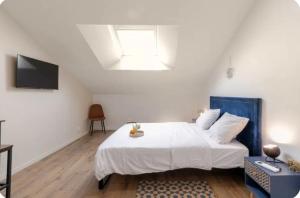 a bedroom with a white bed and a television at Chambre Attrape rêves in Sainte-Geneviève-des-Bois