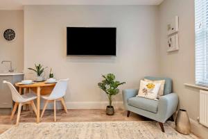 a living room with a table and a chair and a television at Beach Walk Southbourne SOBO Beach Sleeps 4 in Southbourne +33 photos
