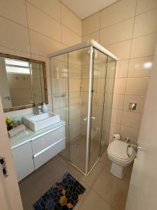 a bathroom with a shower and a toilet and a sink at Loft 102 Farol de Santa Marta in Laguna