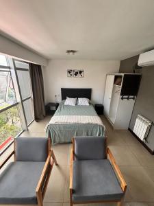 a bedroom with a bed and two chairs in it at monoambiente castelar in Castelar