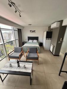 a bedroom with a bed and two chairs and a refrigerator at monoambiente castelar in Castelar