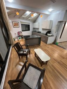 a living room with chairs and a table and a kitchen at Kanakdhara farmhouse in Ujjain