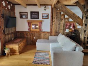 a living room with a white couch and a tv at Oddih v Srčni hiški in Dvor