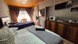 a bedroom with two beds and a tv on the wall at Silhouette Guesthouse in Welkom
