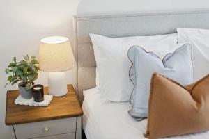 a bed with white pillows and a table with a lamp at The Tobias in Perth