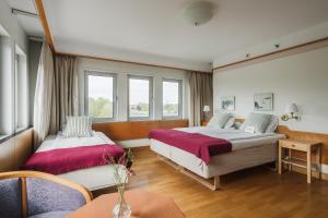 ein Hotelzimmer mit zwei Betten und einem Tisch in der Unterkunft 2Home Stockholm South in Stockholm