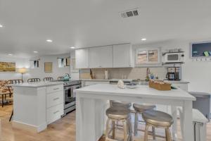 a kitchen with white cabinets and bar stools at Charming Washington Park Getaway in Denver