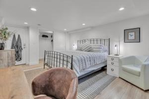 a white bedroom with a bed and a chair at Charming Washington Park Getaway in Denver