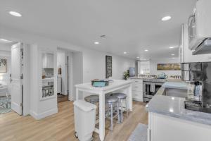 a kitchen with white cabinets and a kitchen island with bar stools at Charming Washington Park Getaway in Denver +15 photos