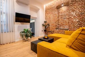 a living room with a yellow couch and a brick wall at Sokak Heritage Apartments in Bitola