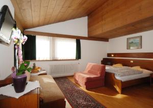 a bedroom with a bed and a chair in a room at Park Hotel Villa Trunka Lunka in Cavalese