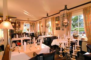 a dining room with white tables and chairs at Dünenhotel am Meer in Warnemünde