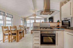 a kitchen with a stove and a table with chairs at Bay View 2-Bed Lodge with Glorious Harbour View and Balcony in Poole