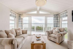 a living room with a couch and chairs and a large window at Bay View 2-Bed Lodge with Glorious Harbour View and Balcony in Poole