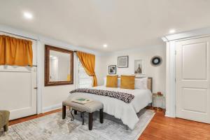 a white bedroom with a bed and a stool at Garden Level 2 bed 2 bath Apartment in Historic District in Savannah