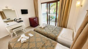 a hotel room with two beds and a desk and a mirror at del Mare Hotel Ölüdeniz in Oludeniz