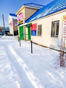 a snow covered street in front of a building at Гостевой дом Москва in Aktobe