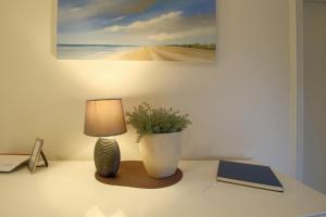 a table with a lamp and a book and a plant at FW2 Deichperle in Wremen