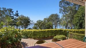 a wooden table and chairs in front of a hedge at Tinaroo Lodge Lakeview Escape with Pool Access in Tinaroo