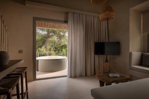 a bedroom with a large window with a tub outside at Domus Gaia Suites in Nikiti