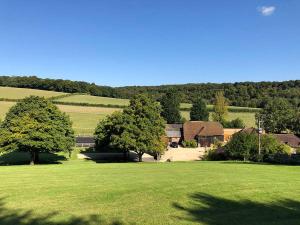 a large green field with trees and a building at Hallbottom Farm Cottage in Stokenchurch