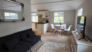 a living room with a black couch and a table at Hallbottom Farm Cottage in Stokenchurch