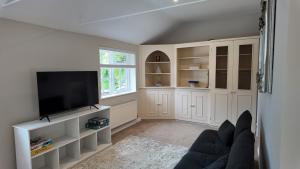 a living room with a couch and a flat screen tv at Hallbottom Farm Cottage in Stokenchurch