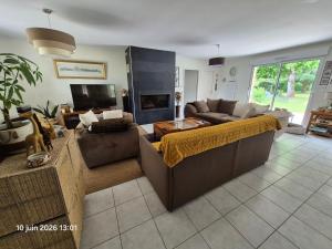 a living room with a couch and a tv at Chambres d'hotes PROCHE CIRCUIT in Arnage