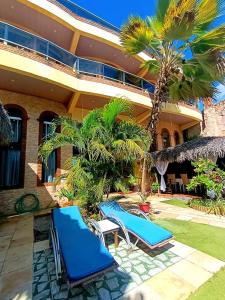 a resort with two blue lounge chairs and palm trees at Pousada Presidente Hotel in Canoa Quebrada