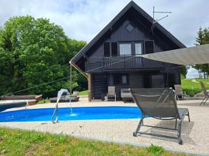 a chair next to a house with a swimming pool at House Gore VVV in Dol pri Hrastniku