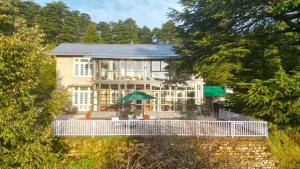 a large house with a white fence in front of it at Deodar Manor - Guest House Khajjiar in Khajjiar 