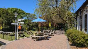 a patio with picnic tables and a blue umbrella at 35 Strawberry Hill, Tolroy Manor in Hayle +6 photos