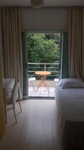 a bedroom with a bed and a table and a balcony at Balkony 407 - Três quartos Perto UNB in Brasilia