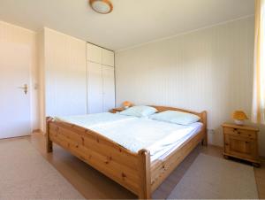 a bedroom with a large wooden bed with white sheets at Wohnung Gesa in Alkersum in Alkersum
