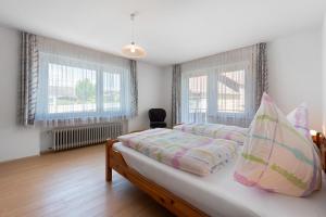 a bedroom with a bed and two windows at Ferienwohnungen Kopp in Hagnau