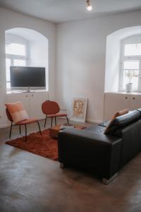 a living room with a couch and chairs and a tv at Historische, moderne Stadtwohnung in Riedlingen