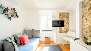 a living room with a couch and a tv at Apartamentos Aurea - Sesimbra in Sesimbra