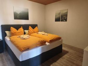 a bedroom with two beds with orange sheets at Pension Malu die hundefreundliche Pension mit Frühstück ab 6 Uhr in Todenbüttel