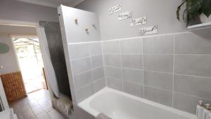 a bathroom with a tub and a white tiled wall at Willowlea Cottage in Underberg