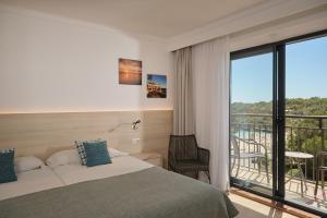 a hotel room with a bed and a balcony at Hotel Playa Mondrago in Portopetro +38 photos