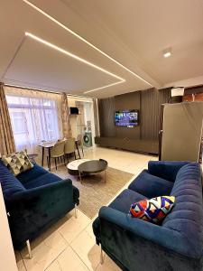 ein Wohnzimmer mit zwei blauen Sofas und einem Fernseher in der Unterkunft Residence Next Door Green Zone in Kiambu