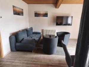 a living room with a couch and a chair and a tv at Pension Malu die hundefreundliche Pension mit Frühstück ab 6 Uhr in Todenbüttel +3 photos