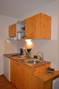 a kitchen with wooden cabinets and a sink at Appartement Orelle spa et piscine in Orelle