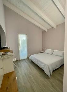 a white bedroom with a bed and a television at Villa Giovanna Rooms in Montelabbate