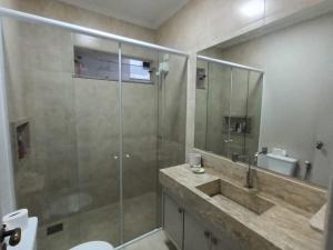 a bathroom with a glass shower and a sink at Confortável e bem localizada, com 2 quartos e garagem in São João da Boa Vista