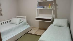 a room with two beds and a shelf at Confortável e bem localizada, com 2 quartos e garagem in São João da Boa Vista
