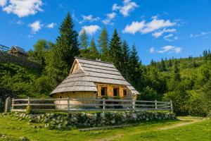 a small house in a field with a fence at Chalet Lepenatka with Sauna - I feel Alps in Stahovica