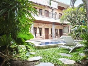 a resort with a pool and a chair in the yard at Sun Homestay Canggu in Canggu