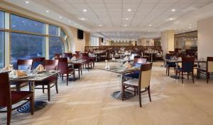 a dining room with tables and chairs and windows at Makarem Umm Al Qura Hotel in Mecca