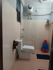 a white bathroom with a toilet and a camera on the wall at Longchen Homestay in Dimapur